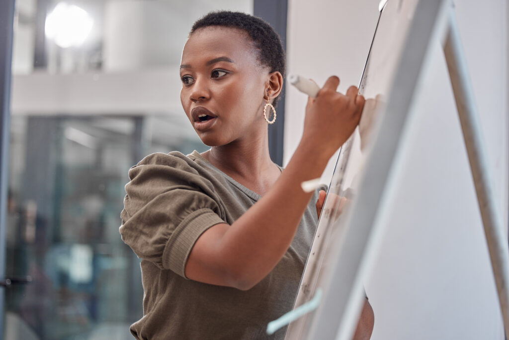 Une femme d'affaires, un conseil d'administration et une femme noire avec une présentation, une planification et un processus d'explication lors d'un atelier. Femme, présentatrice et conférencière écrivant, faisant du brainstorming et de la motivation avec la croissance des bénéfices et le mentorat.